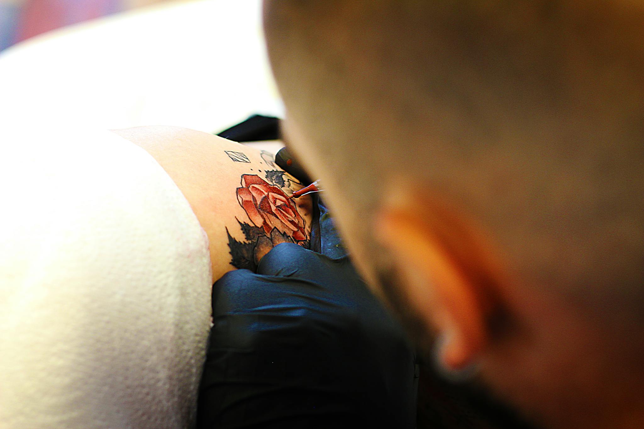A tattoo artist skillfully inking a detailed rose tattoo in a creative process.