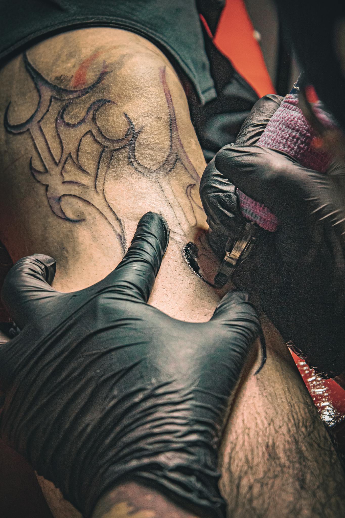Tattoo artist skillfully works on a detailed tribal design with precision and care.