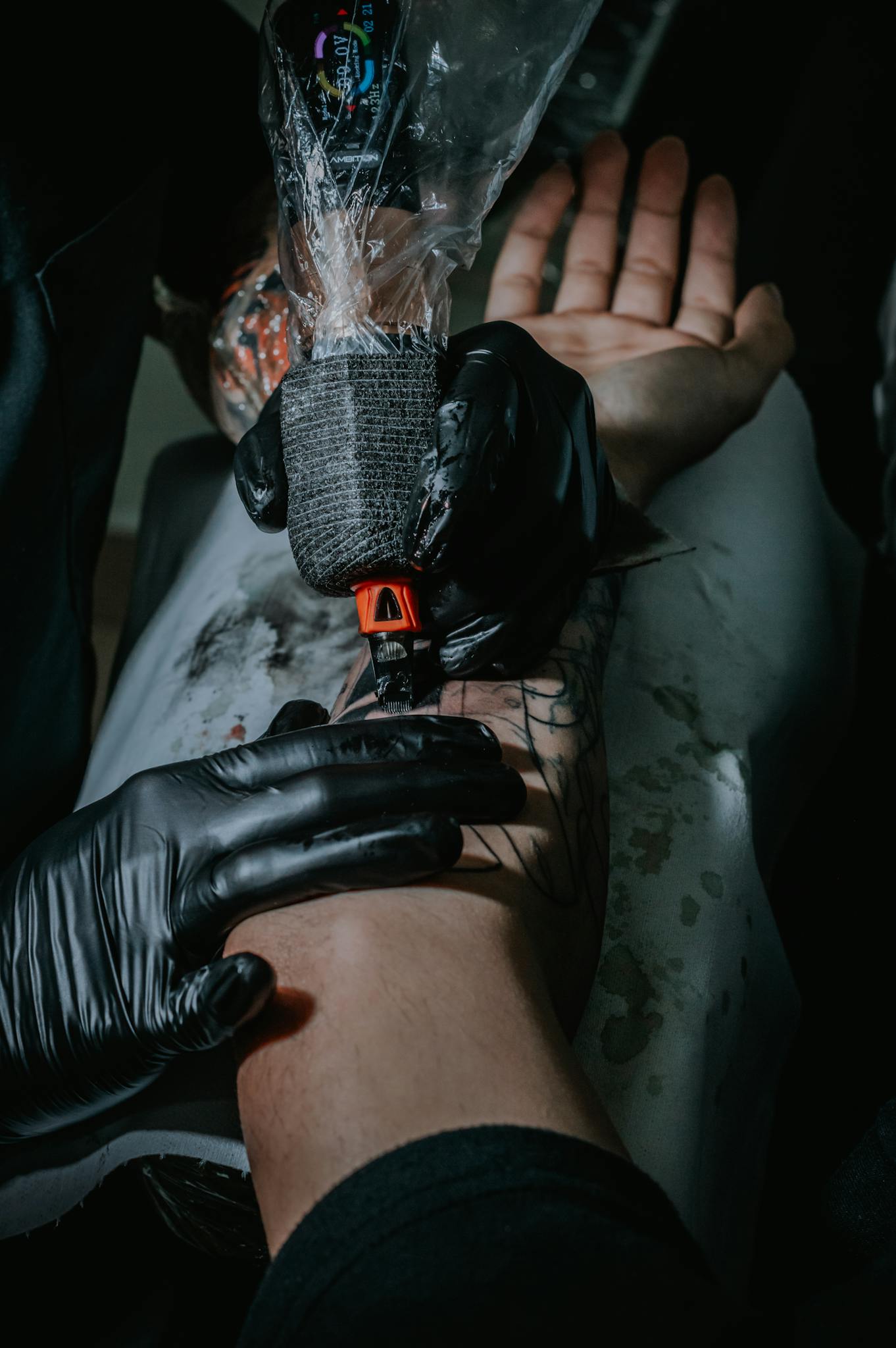 Tattoo artist working meticulously on a client's arm tattoo. Close-up of the tattoo process with gloves and tattoo machine.